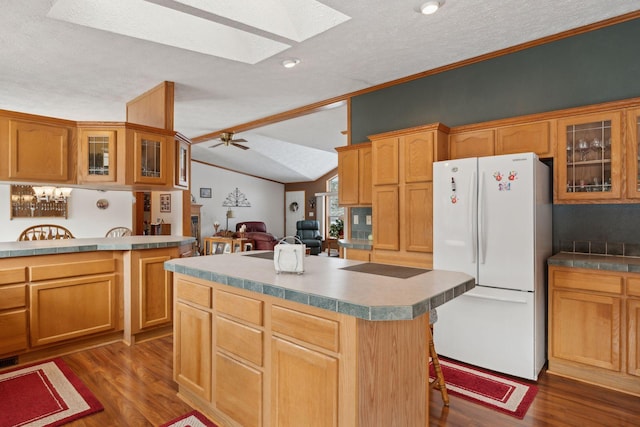 kitchen with a center island, vaulted ceiling with skylight, a kitchen bar, dark hardwood / wood-style flooring, and white fridge