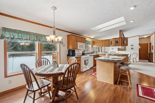 dining space featuring crown molding, a skylight, light hardwood / wood-style flooring, and a textured ceiling