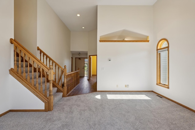 carpeted foyer with a towering ceiling