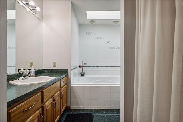 bathroom with vanity, tile patterned flooring, a skylight, and tiled bath