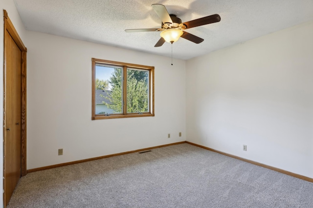 carpeted spare room with a textured ceiling and ceiling fan