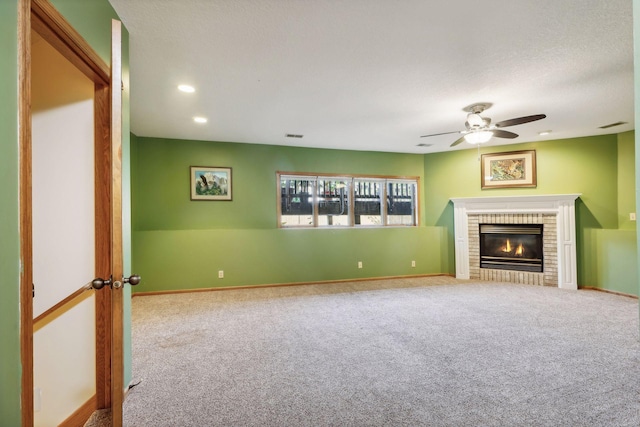 unfurnished living room with a brick fireplace, ceiling fan, and carpet flooring