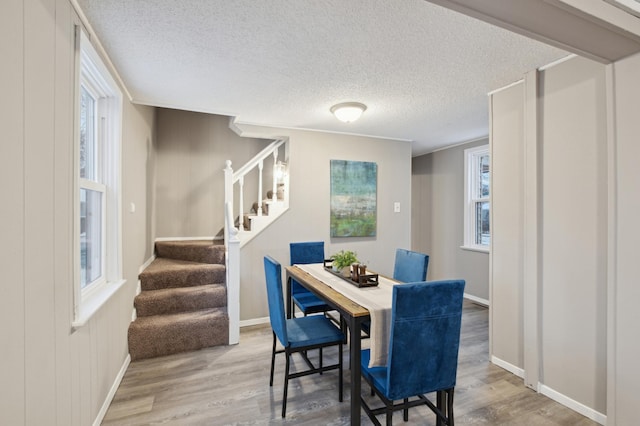 dining space with wood-type flooring and a textured ceiling