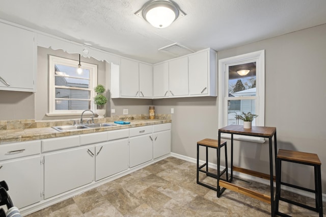 kitchen featuring sink, white cabinetry, and a textured ceiling