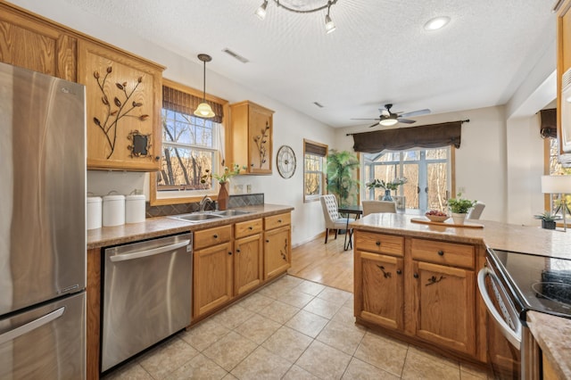 kitchen featuring stainless steel appliances, a healthy amount of sunlight, sink, and decorative light fixtures