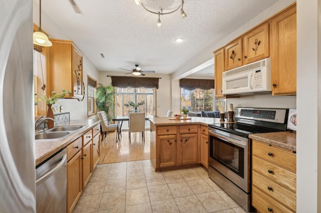 kitchen featuring sink, appliances with stainless steel finishes, light tile patterned flooring, decorative light fixtures, and kitchen peninsula