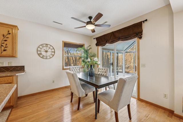 dining space with ceiling fan, light hardwood / wood-style floors, and a textured ceiling