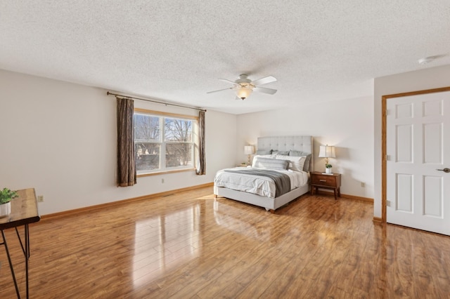 bedroom featuring ceiling fan, light hardwood / wood-style flooring, and a textured ceiling