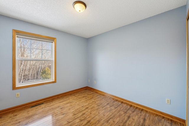 empty room with a textured ceiling and light wood-type flooring