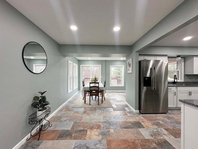 kitchen featuring white cabinets, stainless steel fridge, a healthy amount of sunlight, and sink