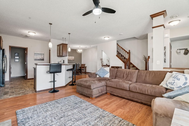 living room featuring a textured ceiling, ceiling fan, sink, and light hardwood / wood-style flooring