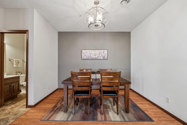 dining room with a chandelier, a textured ceiling, and wood-type flooring