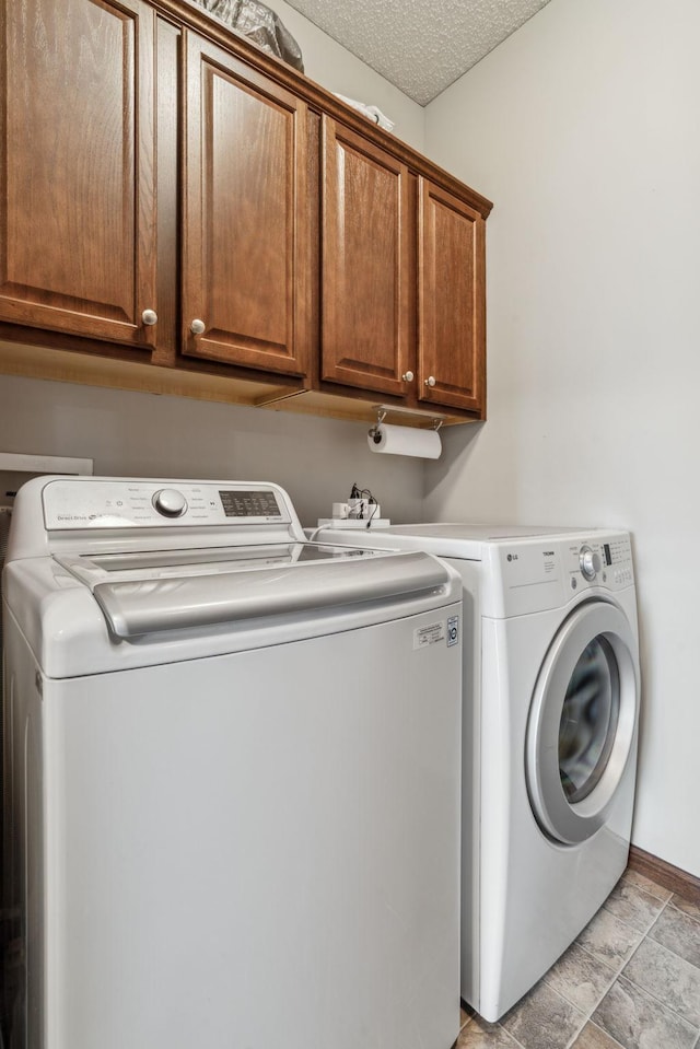 laundry room featuring washing machine and dryer, cabinets, and a textured ceiling