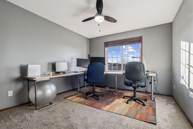 carpeted home office with a textured ceiling and ceiling fan