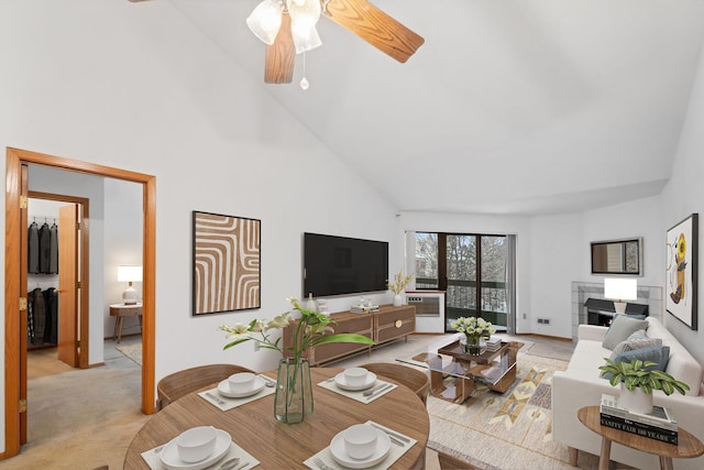 carpeted living room with ceiling fan and high vaulted ceiling