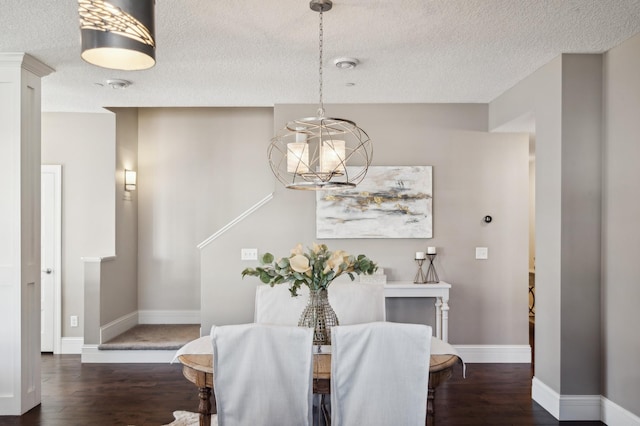 dining room with an inviting chandelier, a textured ceiling, baseboards, and wood finished floors