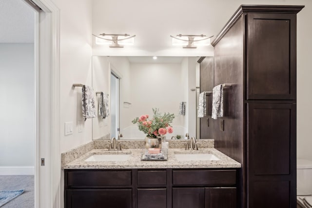 full bathroom with double vanity, toilet, and a sink