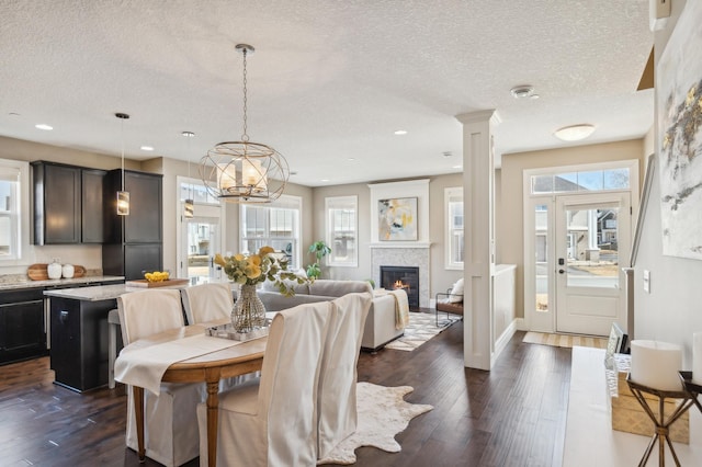 dining space featuring recessed lighting, dark wood finished floors, a textured ceiling, and a glass covered fireplace