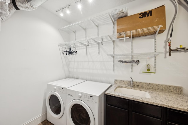 laundry room featuring baseboards, a sink, washer and clothes dryer, and track lighting