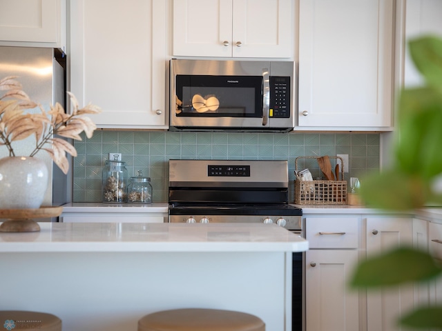 kitchen with appliances with stainless steel finishes, backsplash, and white cabinetry