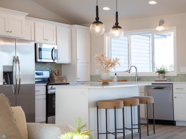 kitchen with stainless steel appliances, hanging light fixtures, lofted ceiling, white cabinetry, and backsplash