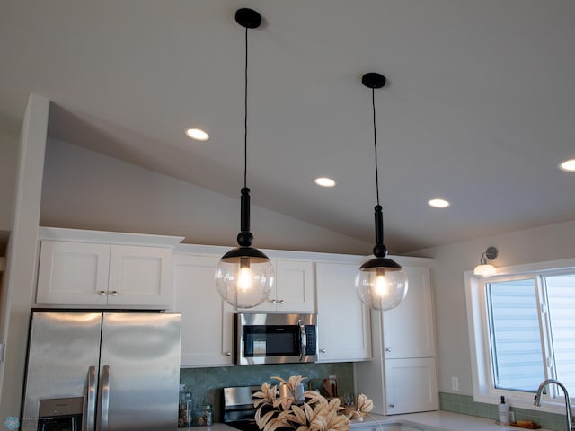 kitchen featuring stainless steel appliances, white cabinetry, backsplash, and hanging light fixtures