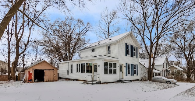 snow covered rear of property featuring a storage shed