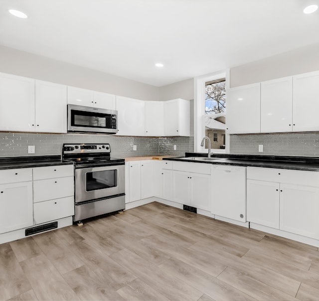 kitchen with sink, white cabinets, stainless steel appliances, and light hardwood / wood-style floors