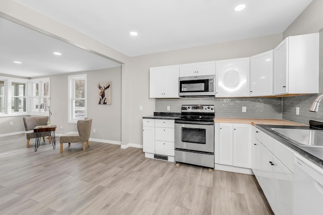 kitchen with white cabinets, sink, stainless steel appliances, and tasteful backsplash