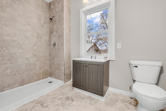 bathroom with tiled shower, vanity, and toilet