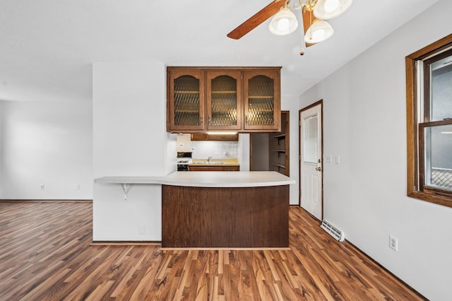 kitchen featuring dark hardwood / wood-style flooring, sink, kitchen peninsula, and ceiling fan