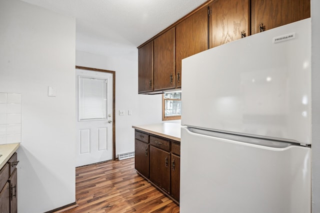 kitchen with dark hardwood / wood-style flooring, a textured ceiling, and white fridge