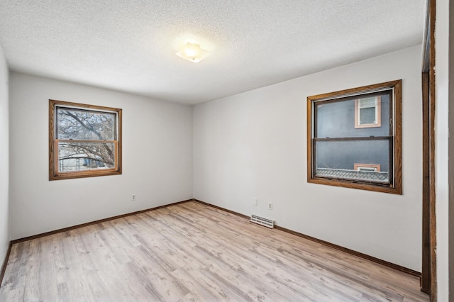 unfurnished room with light hardwood / wood-style flooring and a textured ceiling