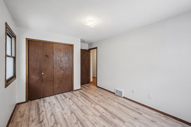 unfurnished bedroom featuring light hardwood / wood-style floors, a closet, and a textured ceiling