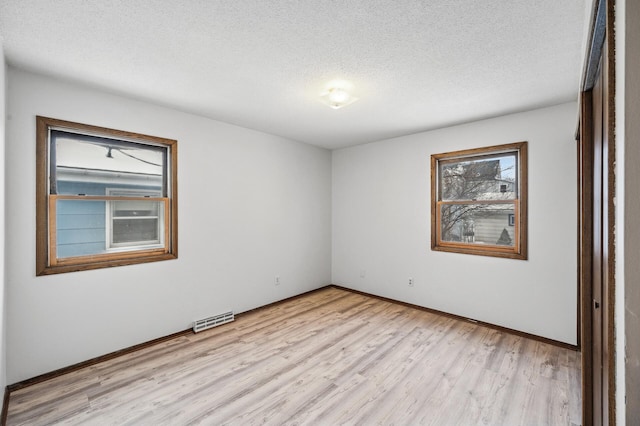 empty room featuring a textured ceiling and light hardwood / wood-style floors