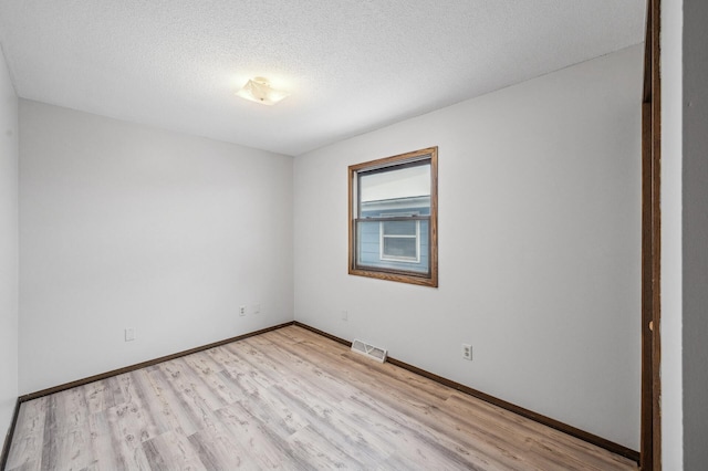 spare room with light hardwood / wood-style floors and a textured ceiling