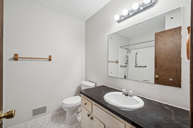 bathroom with vanity, tile patterned floors, toilet, and tiled shower