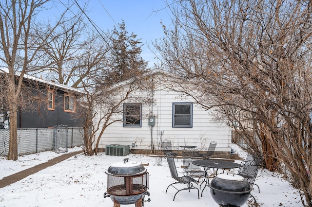 snow covered house featuring central AC unit and an outdoor fire pit