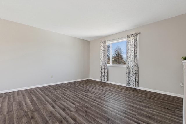 spare room featuring dark wood-type flooring and baseboards