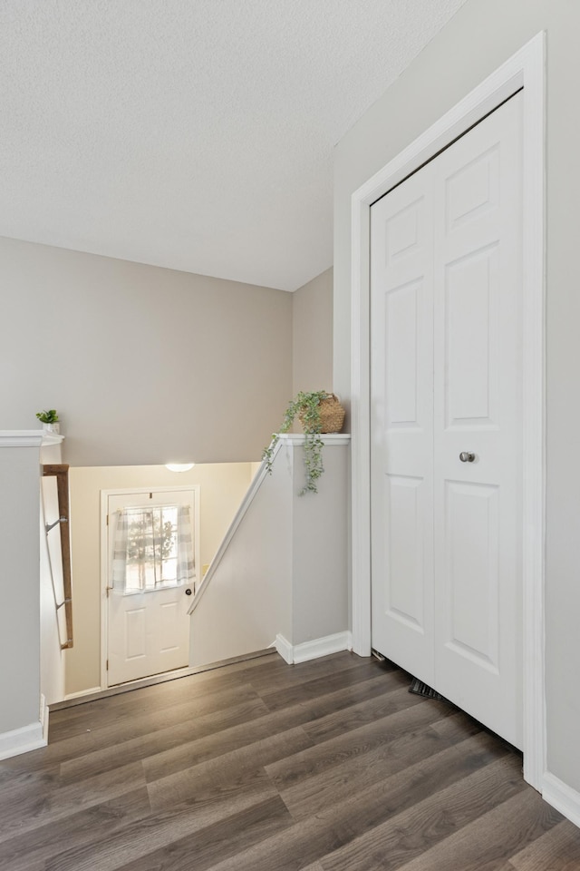 entrance foyer featuring a textured ceiling, baseboards, and wood finished floors