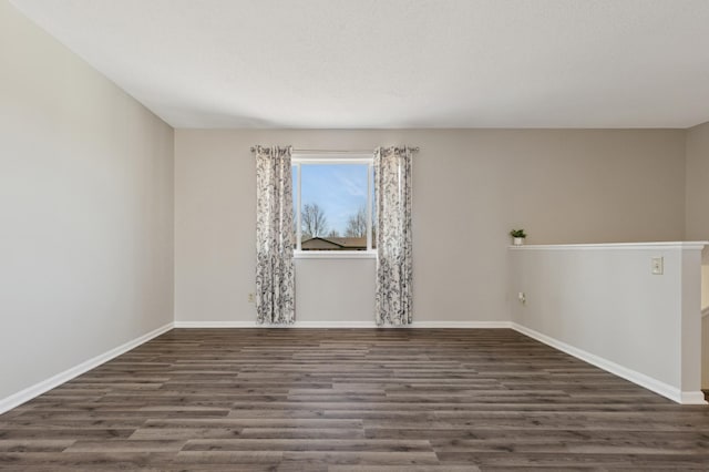 spare room featuring baseboards and wood finished floors