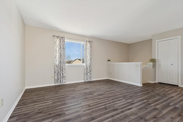 unfurnished room with baseboards and dark wood finished floors