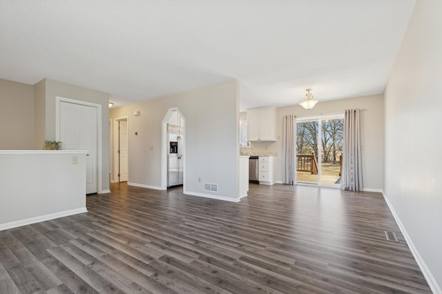 unfurnished living room with dark wood-style floors, visible vents, and baseboards