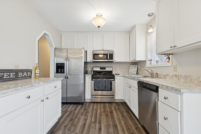 kitchen featuring appliances with stainless steel finishes, white cabinetry, light countertops, and a sink