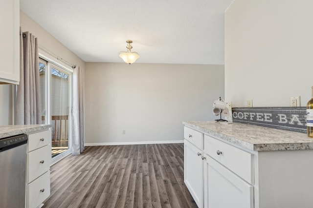 kitchen featuring stainless steel dishwasher, dark wood finished floors, light countertops, and white cabinetry