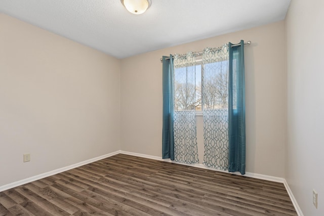 unfurnished room with dark wood finished floors, a textured ceiling, and baseboards