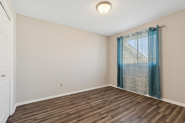 unfurnished room with dark wood-style floors and baseboards