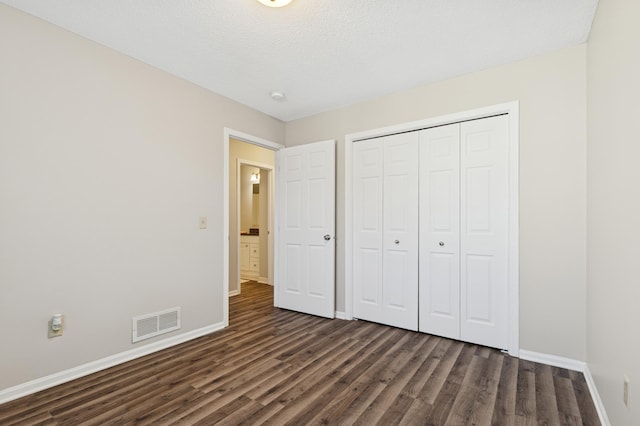 unfurnished bedroom featuring baseboards, visible vents, dark wood-style flooring, and a textured ceiling