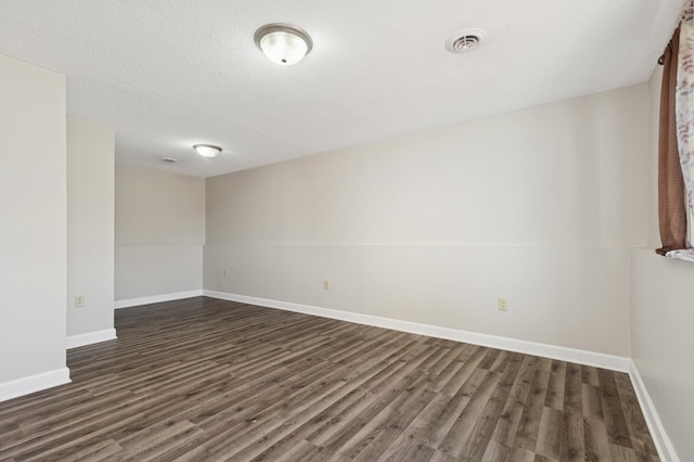 unfurnished room with visible vents, a textured ceiling, baseboards, and dark wood-style flooring