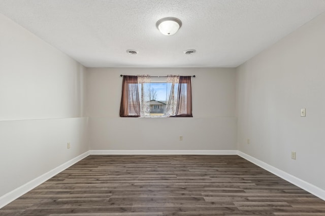 unfurnished room with dark wood-style floors, visible vents, a textured ceiling, and baseboards